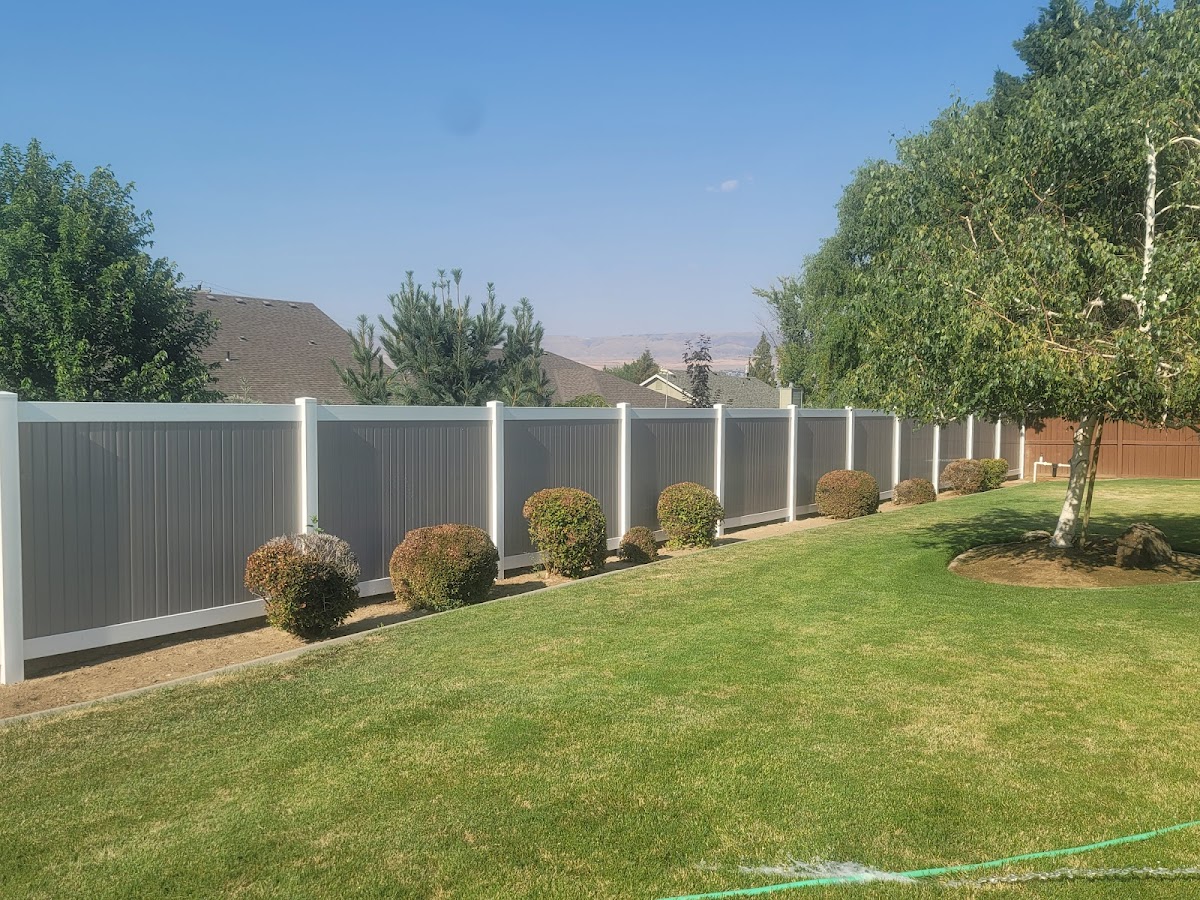A finished vinyl privacy fence along a manicured backyard